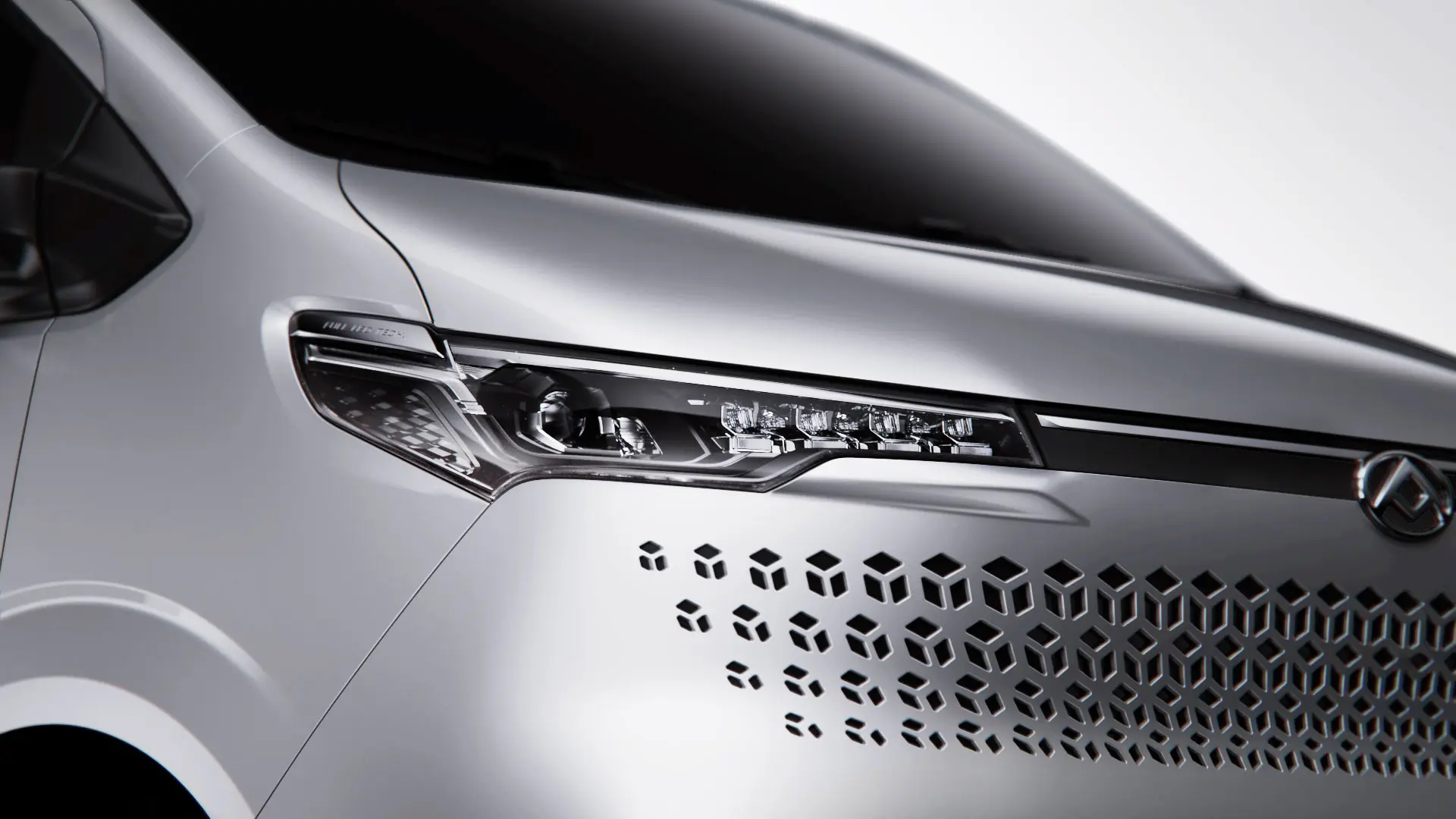 Detailaufnahme eines silbernen Fahrzeugs mit modernen Lichtern und einem grafischen Muster an der Seite.