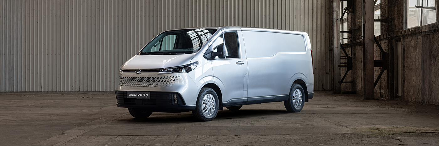Ein silberner Lieferwagen steht in einer großen, leeren Lagerhalle. Der Wagen hat ein modernes Design.